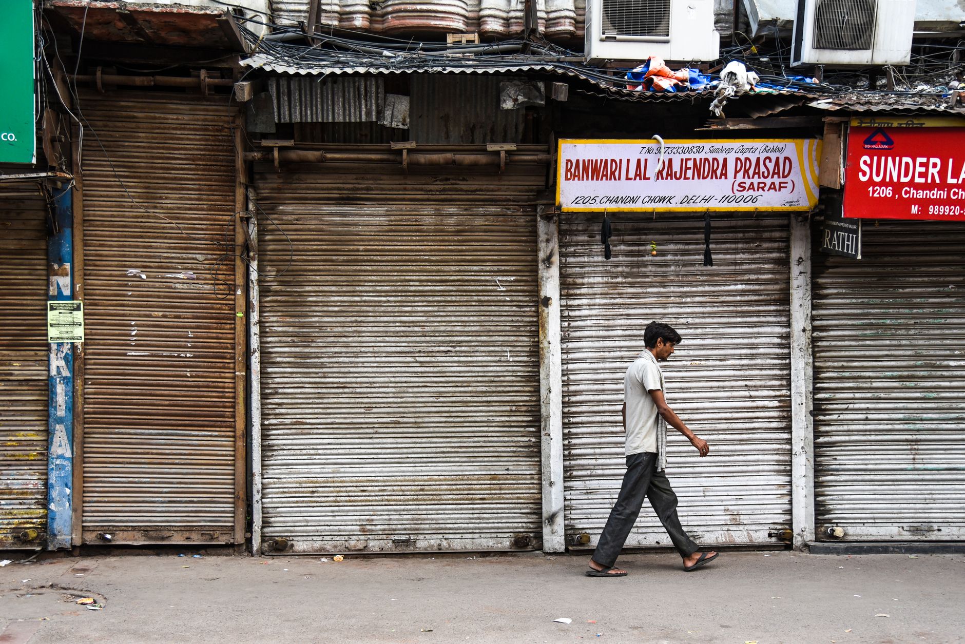 An office worker in India sits at a desk with a laptop, visibly disengaged while colleagues work nearby